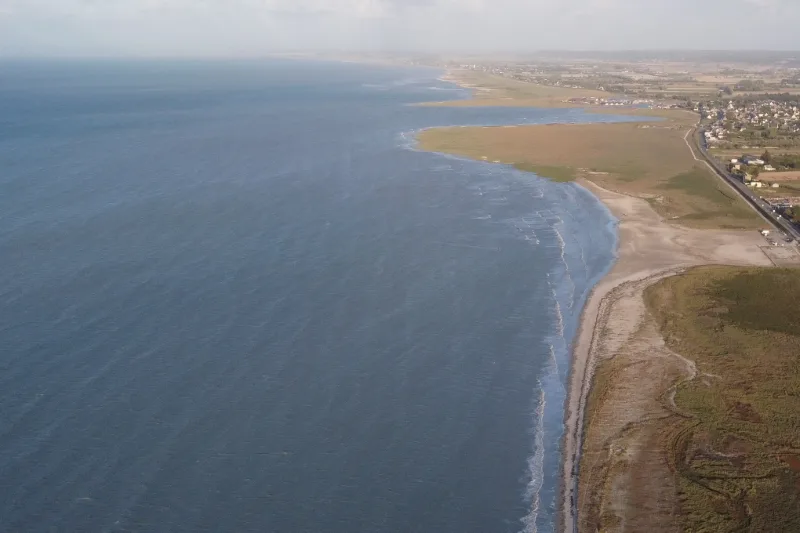 La mer monte sur la grève de la baie, vue du ciel, dans la lumière du soir